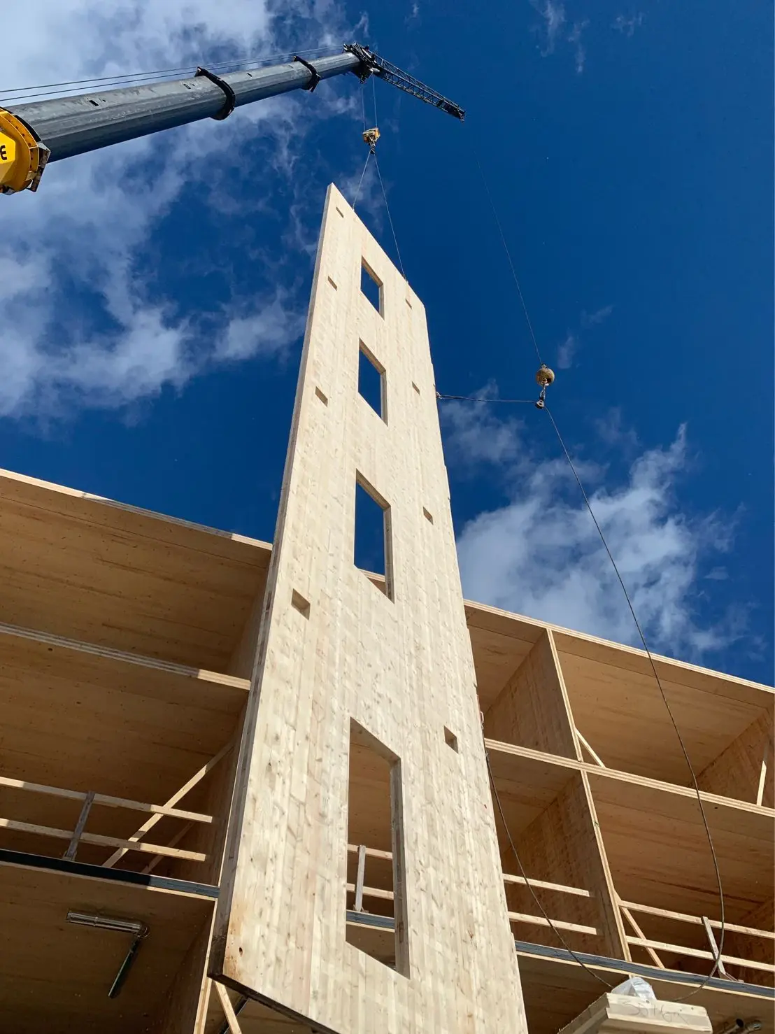 A crane lifting a prefabricated tall wood wall panel
